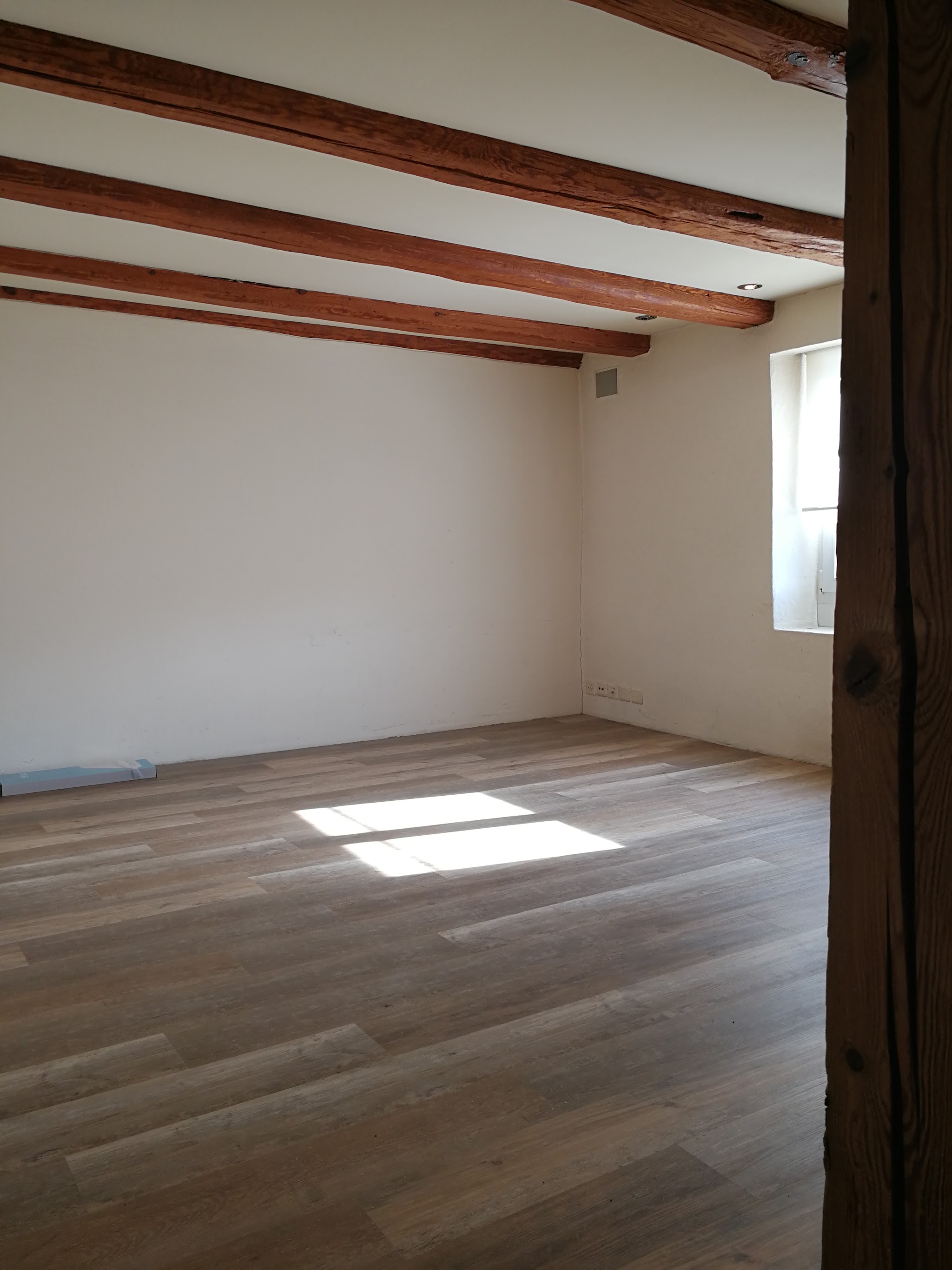 Renovierter Raum mit Parkettboden und sichtbaren Holzbalken