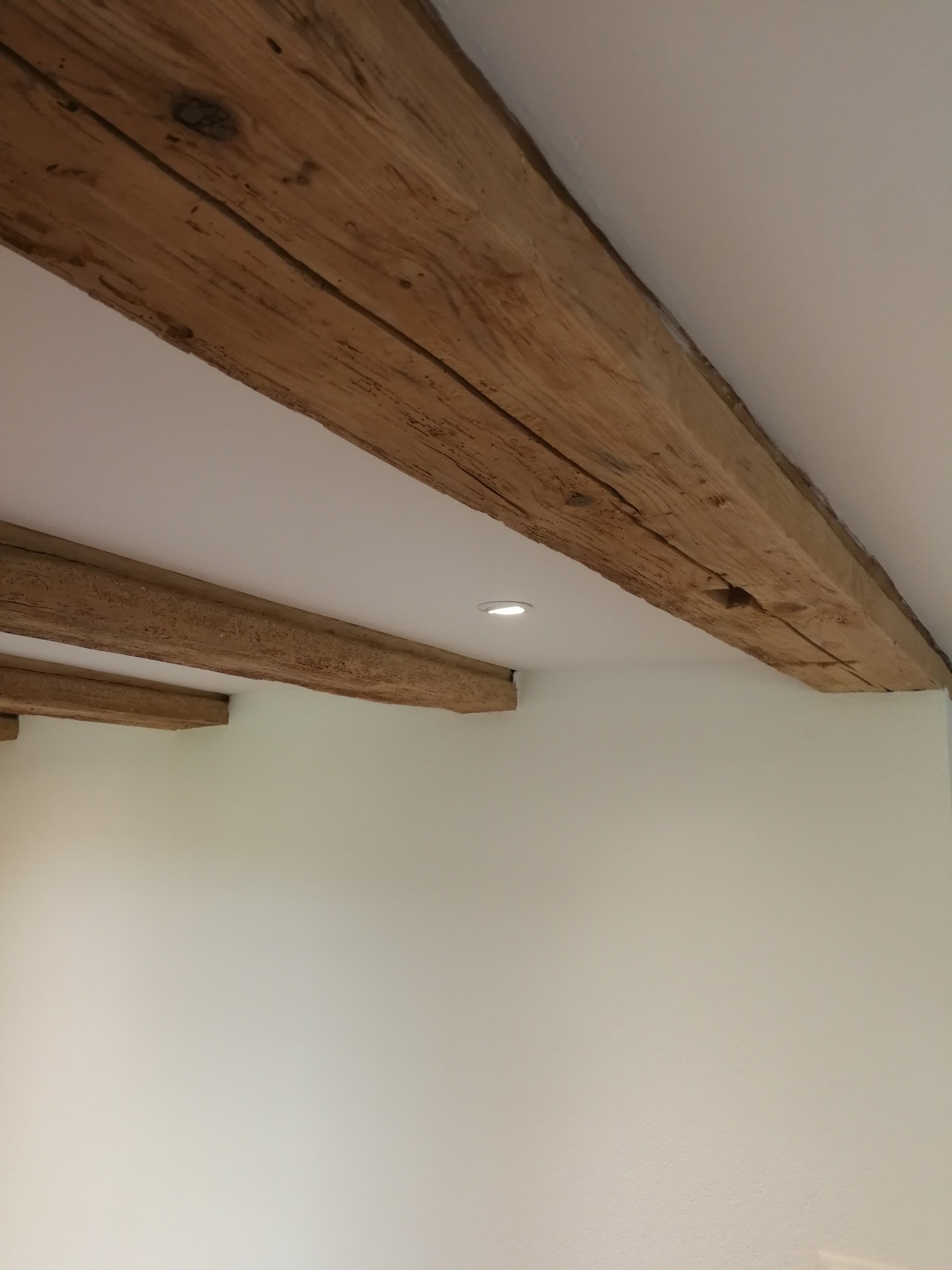 Sichtbare Holzbalken an der weiss gestrichenen Decke