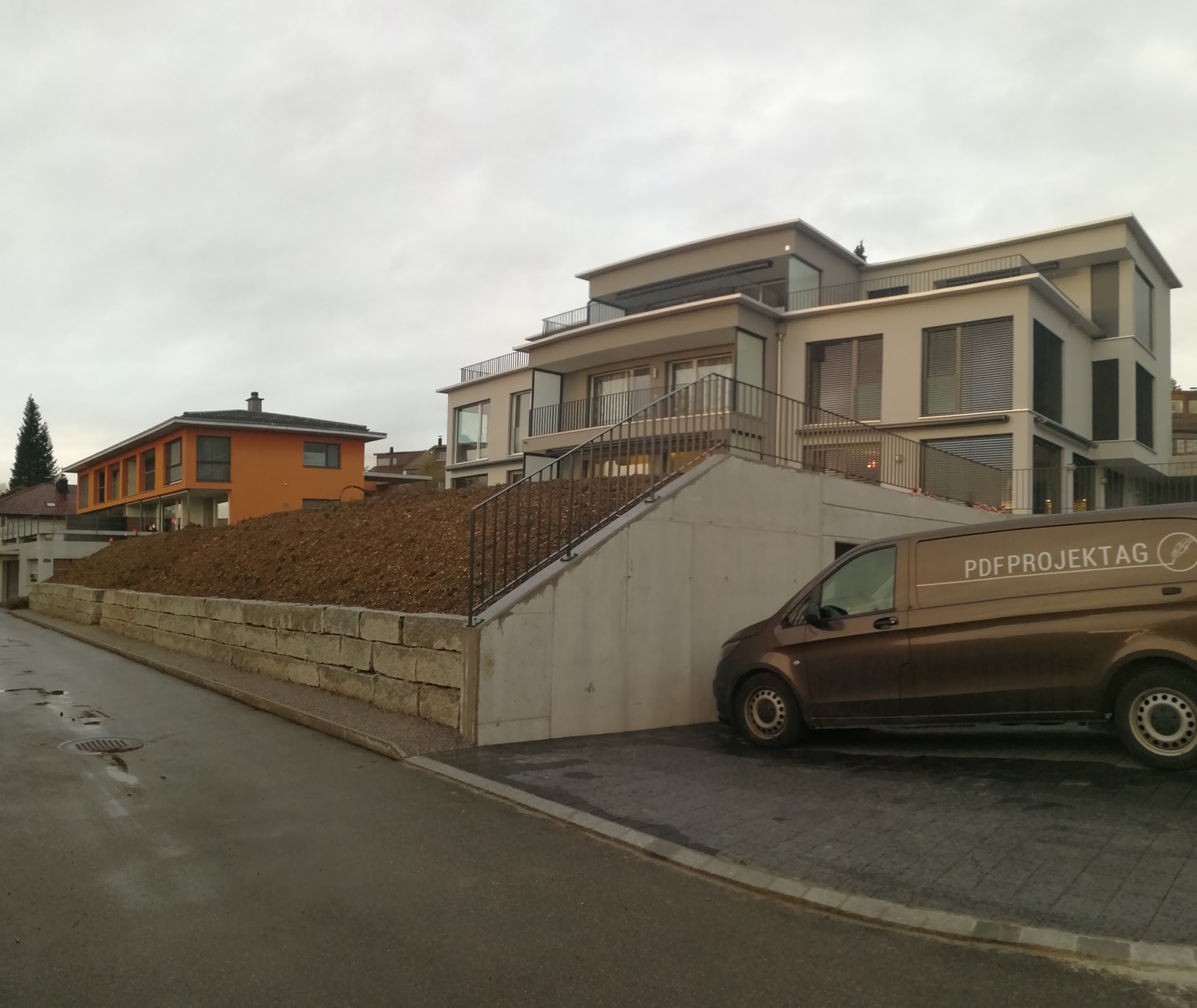 Neubau am Hang mit Firmenbus davor