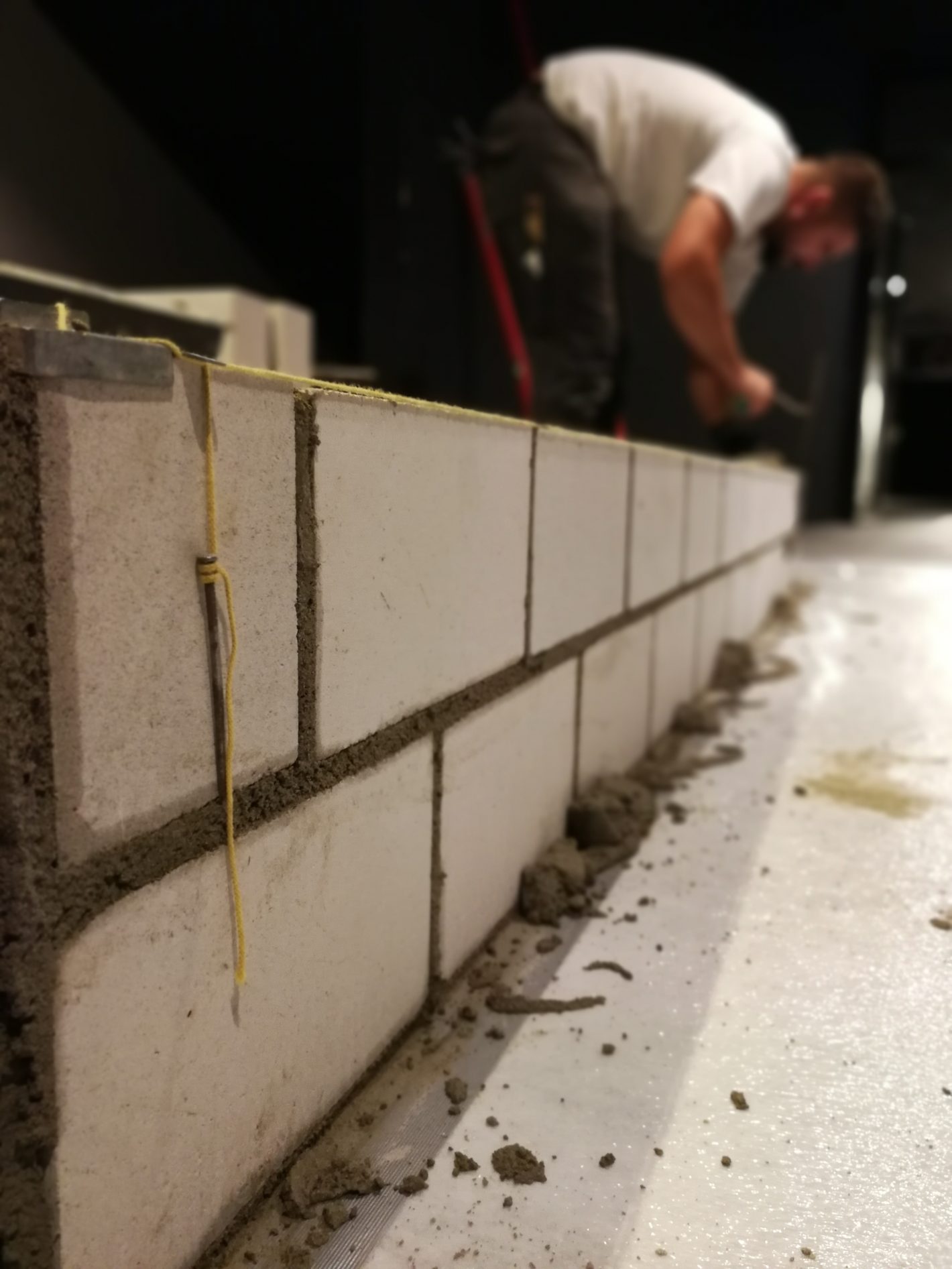 Maurer setzt eine Kalksandsteinwand an der Schnur